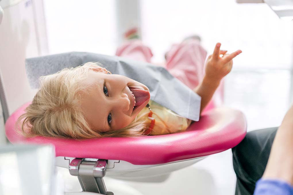 Niña feliz y sacando la lengua en el dentista